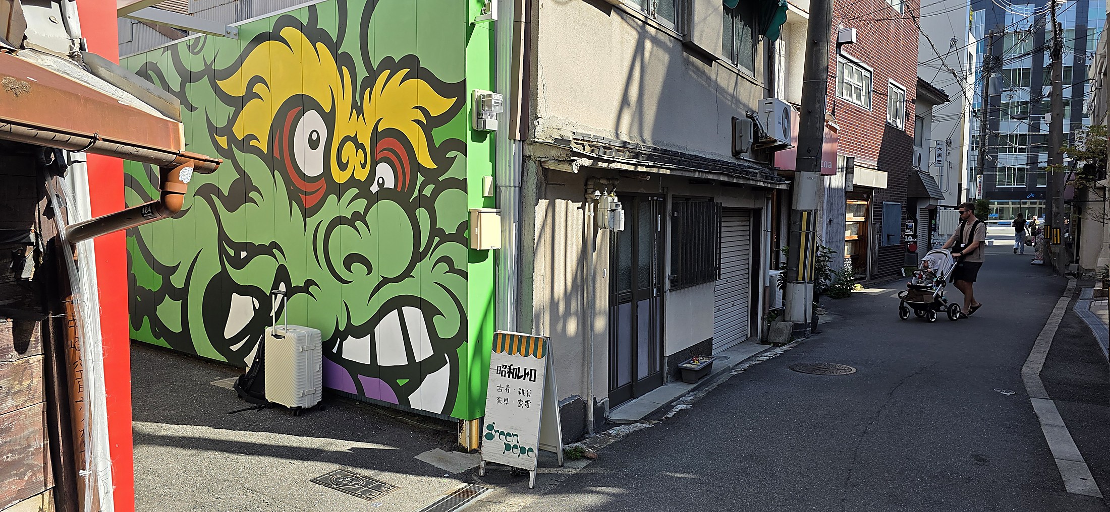 Straßenszene mit kunstvollem Wandbild und Spaziergänger in japanischer Stadt